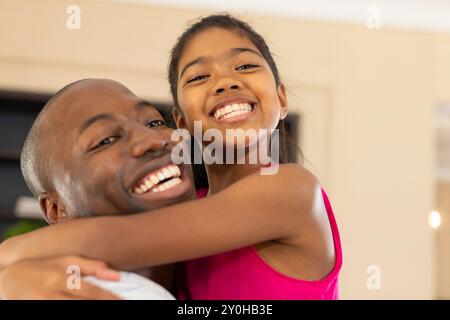 Padre e figlia sorridono e abbracciano, godendo del tempo di qualità in famiglia a casa Foto Stock