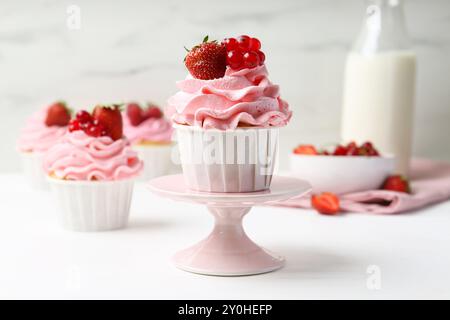 Gustosi cupcake con fragole e ribes rosso sul tavolo bianco Foto Stock