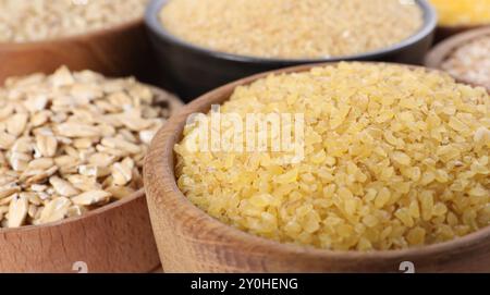 Diversi tipi di cereali in ciotole a tavola, primo piano Foto Stock