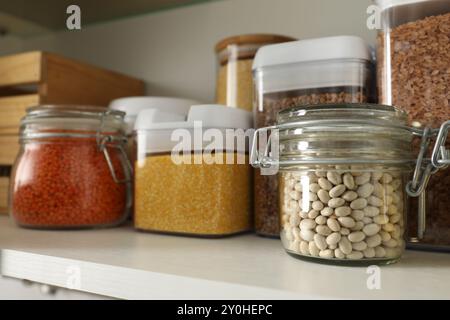 Diversi tipi di cereali e legumi in contenitori sullo scaffale Foto Stock