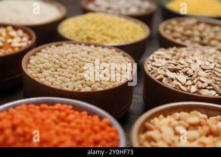 Diversi tipi di cereali e legumi in ciotole sul tavolo, primo piano Foto Stock