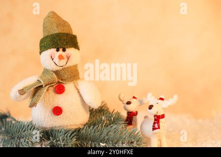 Simpatici pupazzi di neve e cervi con rami di abete sulla neve artificiale Foto Stock