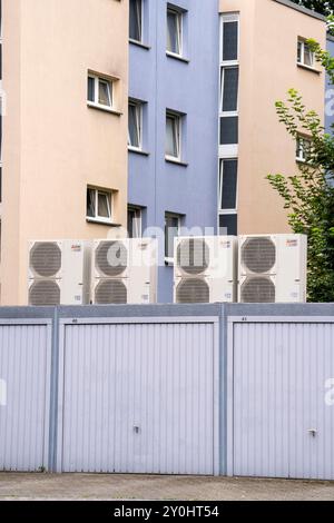 Pompe di calore in un'area residenziale, case multifamiliari sono alimentate con riscaldamento, raffreddamento e acqua calda domestica tramite questi dispositivi, montati su garage r Foto Stock