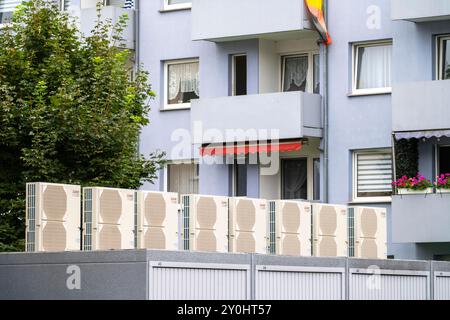 Pompe di calore in un'area residenziale, case multifamiliari sono alimentate con riscaldamento, raffreddamento e acqua calda domestica tramite questi dispositivi, montati su garage r Foto Stock