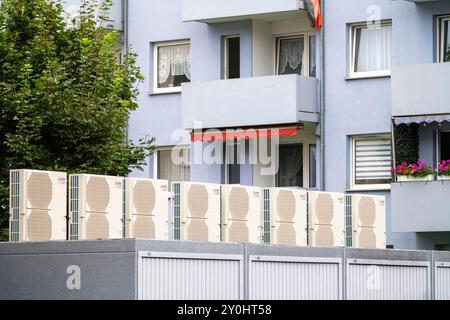 Pompe di calore in un'area residenziale, case multifamiliari sono alimentate con riscaldamento, raffreddamento e acqua calda domestica tramite questi dispositivi, montati su garage r Foto Stock