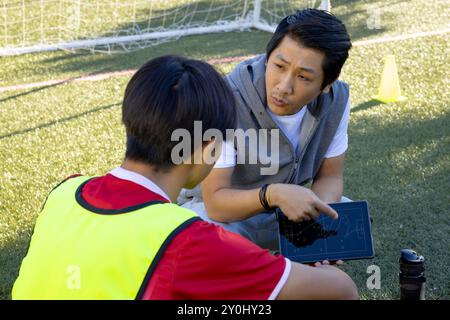 Allenati con un tablet per spiegare la strategia al giovane calciatore adolescente sul campo Foto Stock