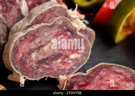 Salame di maiale a fette non sbucciato con spezie, salsiccia di maiale fresca e deliziosa durante la cottura Foto Stock