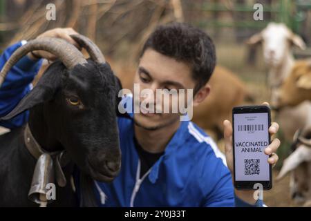 Ritratto di un veterinario che mostra il certificato di vaccinazione di una capra su un telefono cellulare Foto Stock