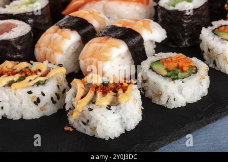 Ampio set di sushi da vicino. Maki, nigiri e rotoli su una ardesia nera Foto Stock