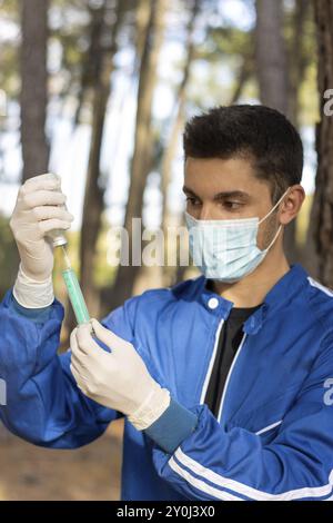 Veterinario in uniforme che prepara un vaccino in un'azienda per vaccinare gli animali, sfondo naturale verticale Foto Stock