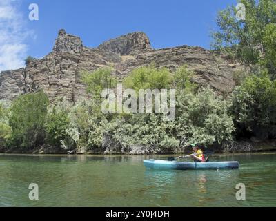 Una giovane donna sta pagaiando vicino al litorale roccioso sul fiume Snake a Twin Falls, Idaho Foto Stock