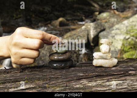 Un primo piano della mano di una donna che mette una piccola pietra su un mucchio di roccia per fare un cairn nel nord dell'Idaho Foto Stock