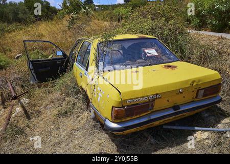 Giallo, vecchia auto lasciata indietro, ricoperta di erbacce in estate, veicolo distrutto, Creta, Isole greche, Grecia, Europa Foto Stock