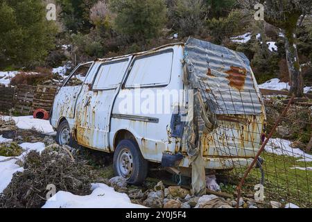 Vecchio furgone arrugginito in un paesaggio innevato e circondato da alberi, relitto di veicoli, Creta, isole greche, Grecia, Europa Foto Stock