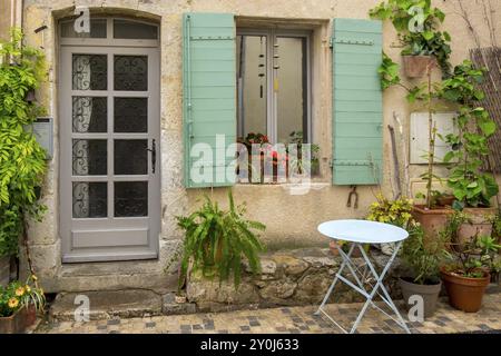 Una facciata di una vecchia casa con persiane verdi, numerose piante e una piccola tavola rotonda, Vauvenargues, Provence-Alpes-Cote d'Azur, Francia, Europa Foto Stock