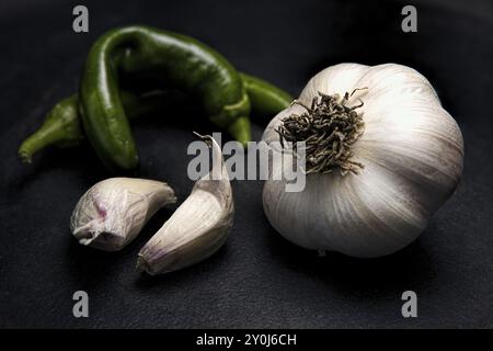 Una foto di uno studio d'arte di un bulbo d'aglio crudo, un paio di chiodi di garofano e peperoncino verde Foto Stock