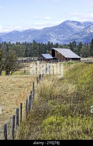 Un vecchio fienile in un pascolo con le montagne della missione sullo sfondo vicino a St. Ignatius, Montana Foto Stock