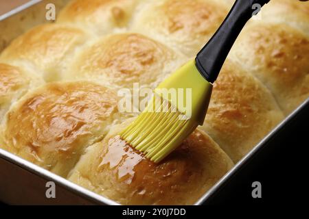 Applicare del burro su panini da cena appena sfornati Foto Stock