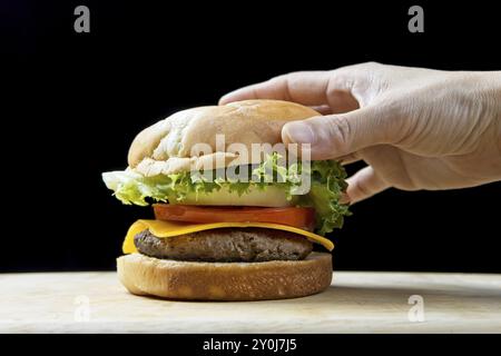 Mettere il panino di qualità su un delizioso cheeseburger in un ambiente da studio Foto Stock