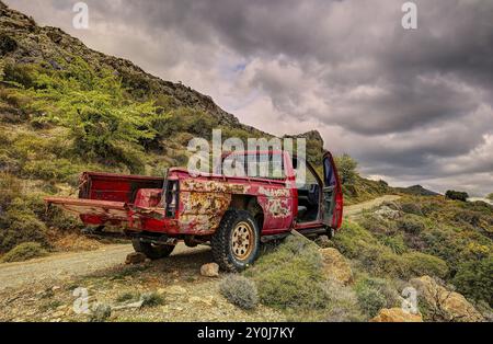 Un vecchio pick-up arrugginito in natura montagnosa sotto un cielo nuvoloso, veicolo distrutto, Creta, Isole greche, Grecia, Europa Foto Stock