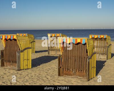 Diverse sedie a sdraio si trovano sulla spiaggia sabbiosa che si affaccia sul mare calmo in una giornata limpida e soleggiata, egmond aan zee, paesi bassi Foto Stock