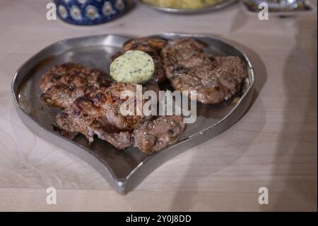 Bistecche di maiale arrosto con aglio servite su un piatto di peltro a forma di cuore, Norimberga, Franconia media, Baviera, Germania, Europa Foto Stock