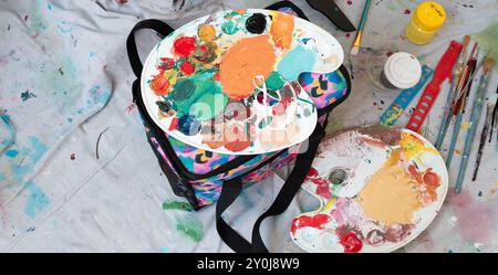 Tavolozza di miscelazione dei colori degli artisti e vari strumenti utilizzati, tra cui pennelli e vernici. Foto Stock