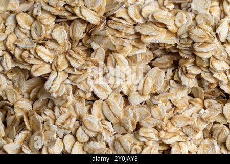 Versò una grande quantità di fiocchi di avena primo piano, sfondo di farina d'avena cruda cruda Foto Stock