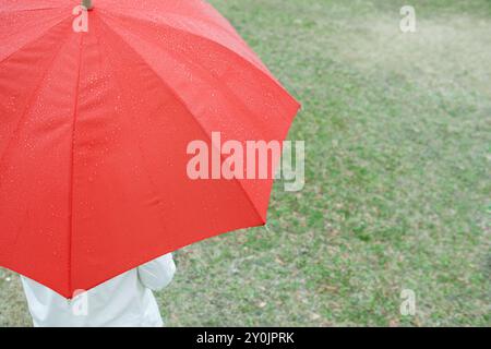 Donna che indossa un ombrello rosso in un giorno di pioggia Foto Stock