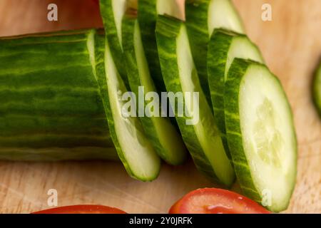 Cetriolo lungo verde a fette durante la preparazione dell'insalata, preparazione dell'insalata con verdure tagliate a pezzetti di cetrioli verdi Foto Stock