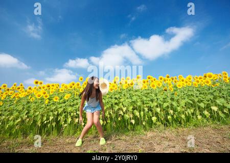 Ragazza che salta allegramente nel campo di girasole Foto Stock