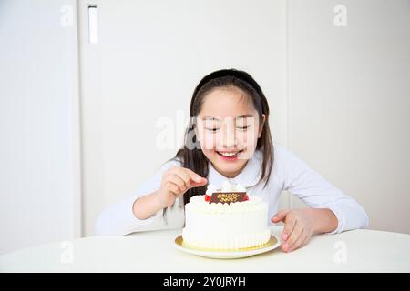 Ragazza che cerca di togliere le fragole da una torta Foto Stock