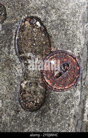 tombini e scarpe stampati in cemento Foto Stock
