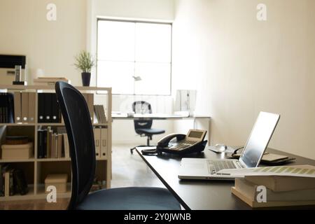 Due scrivanie posizionate vicino alla finestra e ai documenti e un personal computer sulla scrivania della libreria in una stanza bianca Foto Stock