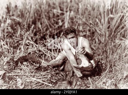 Henry Charles 'Alligator Boy' Coppinger Jr. (1898-1975) con un alligatore catturato nella zona del fiume Miami, nel sud della Florida, il 28 gennaio 1921. Coppinger "inventò" la lotta contro gli alligatori e la insegnò agli indiani Seminole che fecero il loro rituale come attrazione per i turisti all'inizio del XX secolo. (USA) Foto Stock