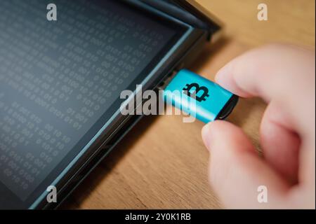 Portafoglio hardware per criptovaluta collegato a un laptop in mano all'uomo. un modo freddo per archiviare le criptovalute su un vettore portatile è un modo per proteggere savin Foto Stock