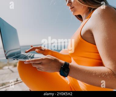 Donna che lavora su un notebook con vestito arancione Foto Stock