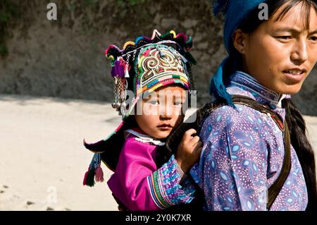 La madre colorata Hmong ( Miao ) e suo figlio stanno andando al mercato settimanale dello Yunnan, in Cina. Foto Stock