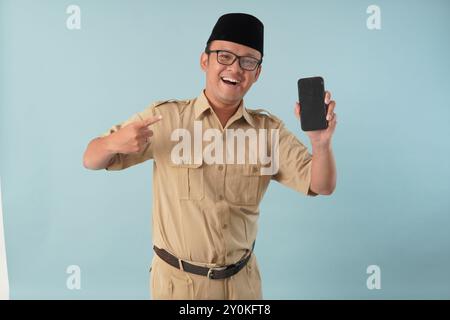 Un dipendente del governo indonesiano eccitato che indossa l'uniforme kaki e presenta uno spazio di copia sul suo smartphone. Concetto di funzionario pubblico PNS. Foto Stock
