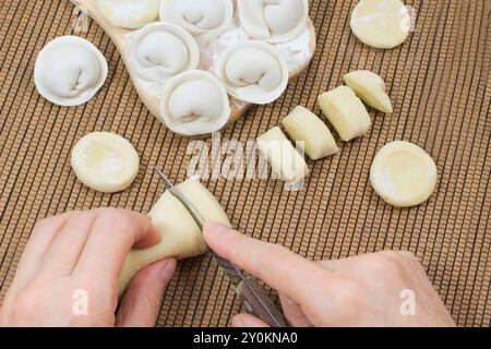 Tagliare l'impasto a pezzi con le mani. Gnocchi crudi sul tabellone Foto Stock