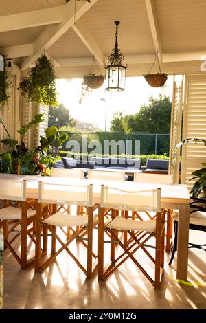Area pranzo con tavolo e sedie in legno, luce del sole che scorre attraverso le finestre Foto Stock