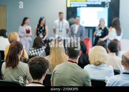 Professionisti aziendali che partecipano a una conferenza e ascoltano una tavola rotonda. Partecipanti impegnati nell'apprendimento e nel networking in un ambiente aziendale. Foto Stock