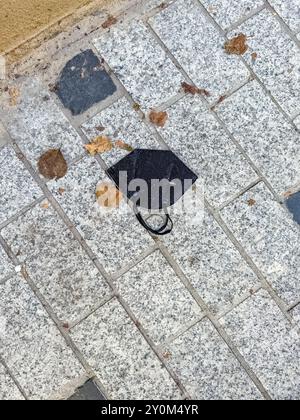 Usato, sporco e nero vecchia maschera medica, si trova sulla strada come una spazzatura. Foto di alta qualità Foto Stock