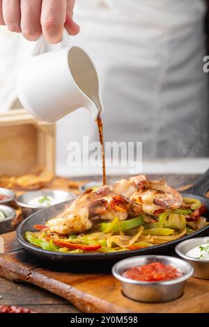 Fajitas di gamberi su un tavolo di legno con salse e tortillas a lato Foto Stock