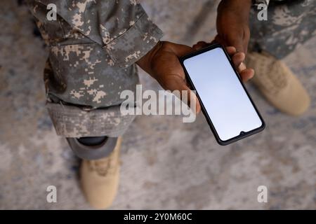 Tenendo in mano lo smartphone, la persona in uniforme militare con protesi alle gambe sedute, spazio di copia Foto Stock