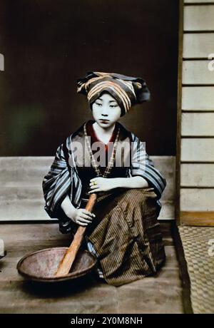 Ragazza con pestello e mortaio 1870 foto giapponesi in bianco e nero colorate a mano Giappone fine XIX secolo Yamamoto Studio fotografia d'albume d'epoca ( storia storica ) riproduzione digitale migliorata. Foto Stock