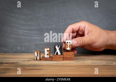 AVANTI. Lettere di legno, blocchi alfabetici sui gradini. concetto di sviluppo e crescita. Foto Stock