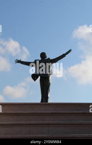 Statua di Domenico Modugno a Polignano a Mare, Puglia, Italia. Bellissimo sfondo del cielo. Foto Stock