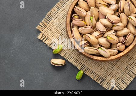 Pistacchi arrostiti in ciotola su un tavolo in legno rustico grigio, noce sano Foto Stock