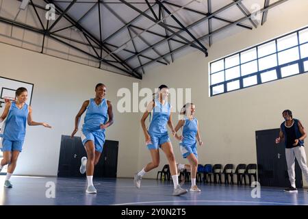 Giocando a basket, giocando a squadre in campo con coach nella palestra scolastica Foto Stock